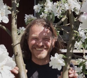 Peter 'Hagge' Hajdu från KFUM Ängsholmen står vid ett blommande fruktträd och ler in i kameran.