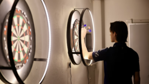 En ung person står och räknar poängen på en darttavla. 