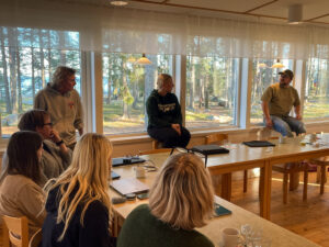 Sjur personer sitter kring ett bord och diskuterar. 